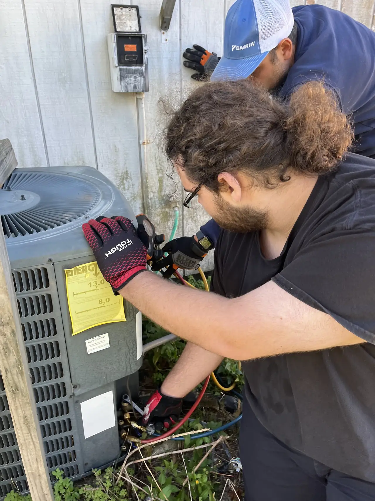 Two Synergie technicians diagnosing an outdoor condenser