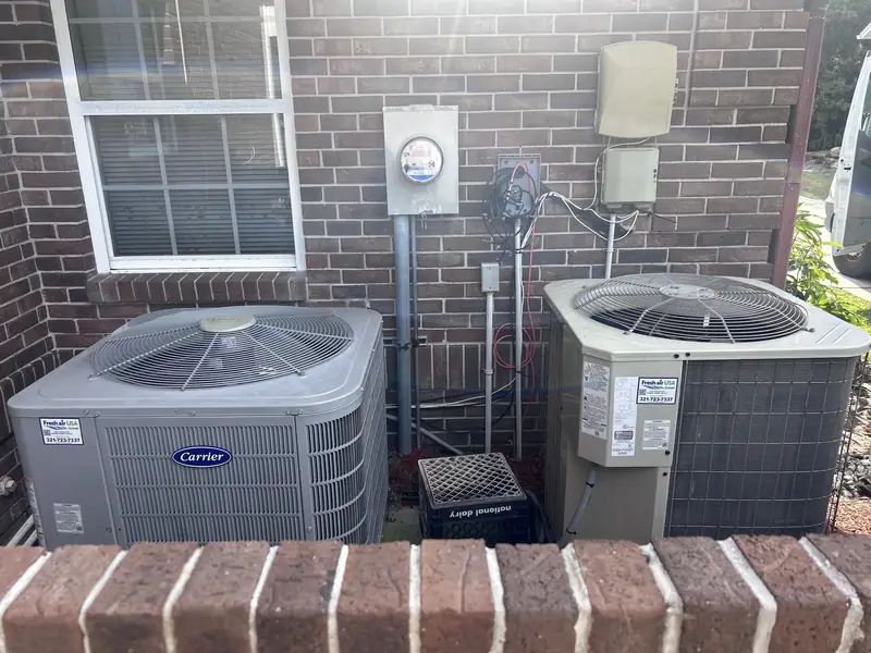 Two residential condensers beside a brick home