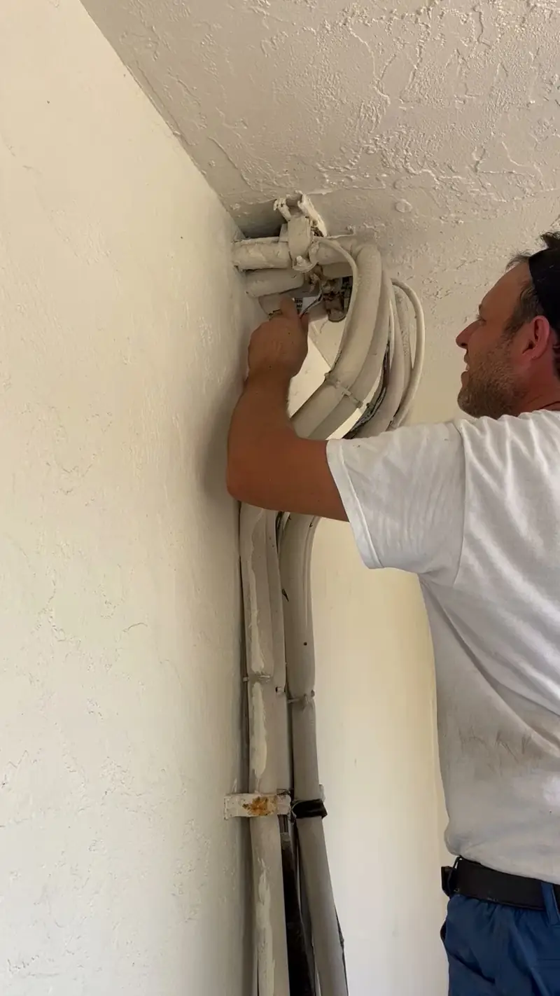 Technician routing refrigerant line set through an exterior wall